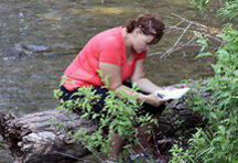 Photo: Student Reading By Stream Photo: Student Reading By Stream