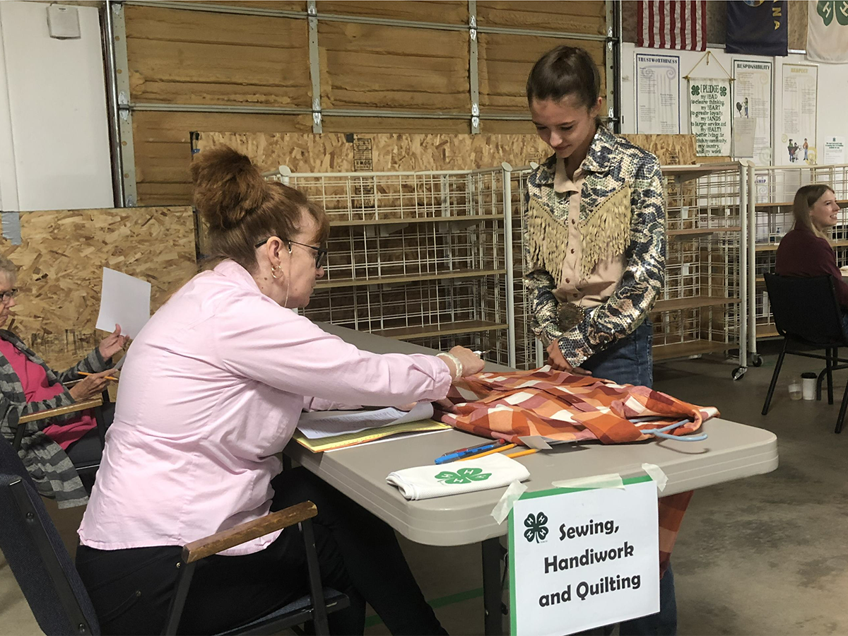 A young girl showing a woman her quilting work at a table