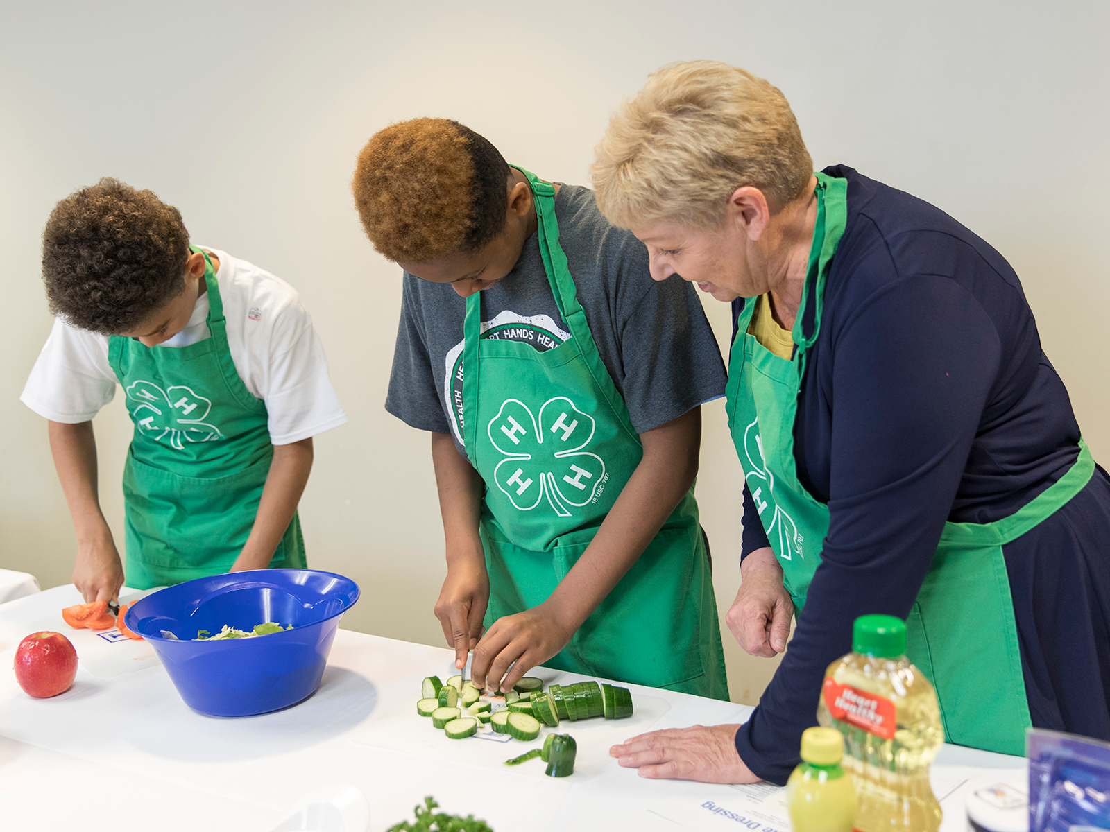 Two 4-H members making food with a volunteer