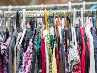 Thrifting feature image An array of shirts in different colors and styles hang on a clothing rack.