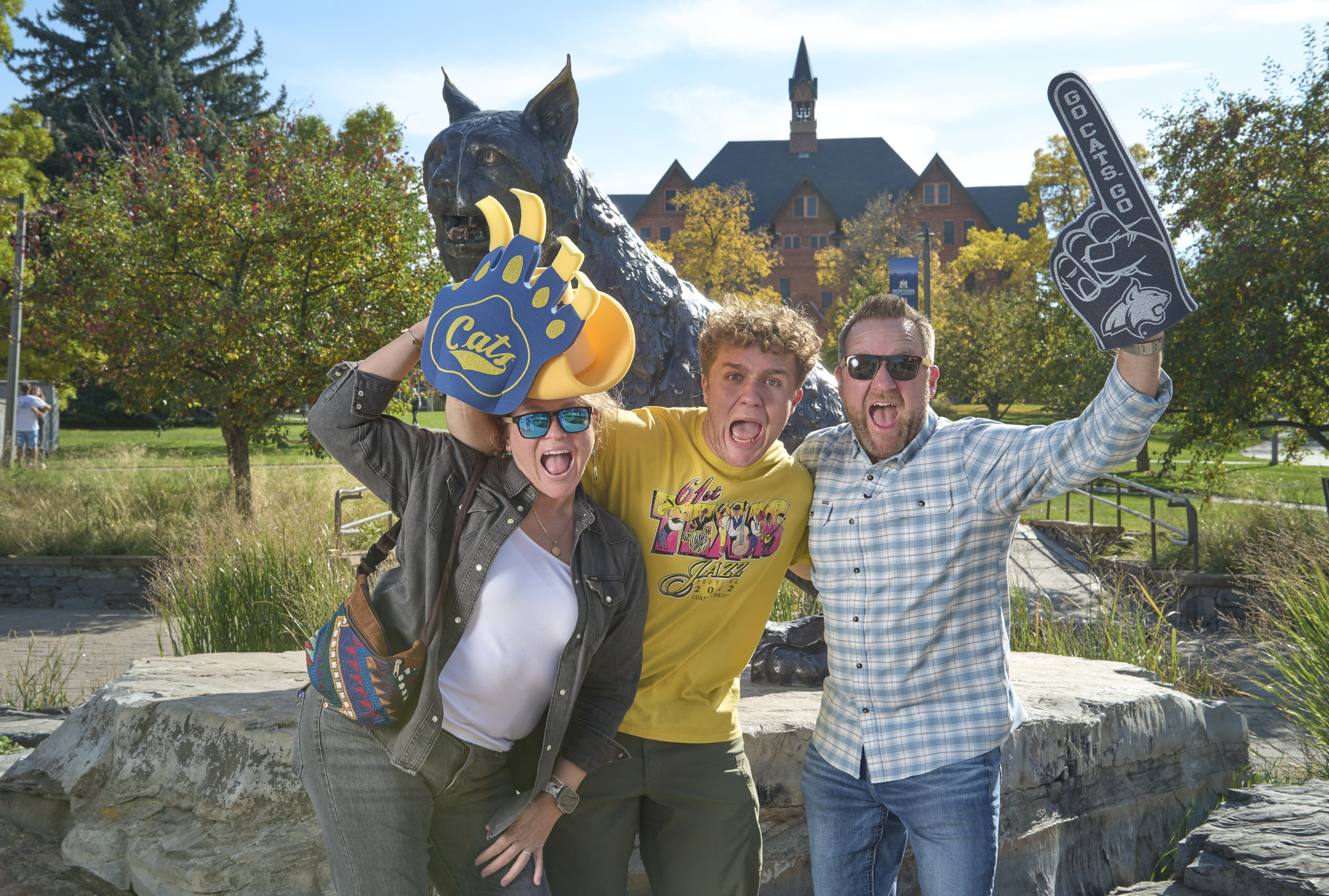 student with parents in front of bobcat statue