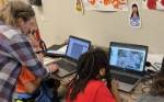 Mentor assists students working at computer stations.