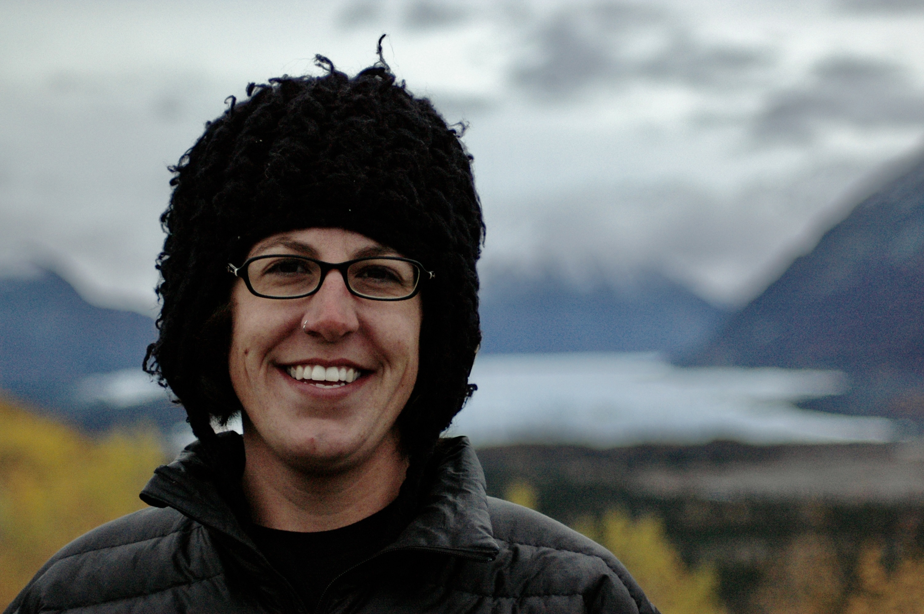 Female student with glasses, standing outside with mountains behind her